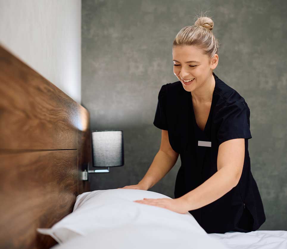 Zimmermädchen beim Betten machen im Hotelzimmer
